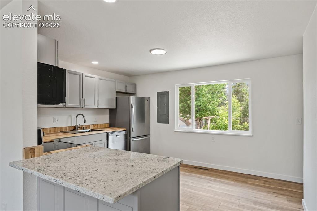 Image 12 of 35: Kitchen featuring light gray cabinetry, stainless steel appliances, wood-fi