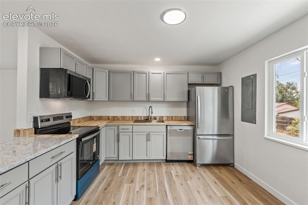 Image 13 of 35: Kitchen featuring light grey cabinetry, stainless steel appliances, wood-fi