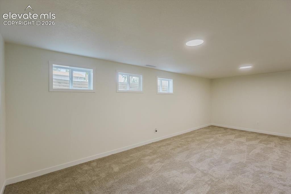 Image 14 of 27: Spacious room featuring neutral carpeting, light-toned walls, and multiple 