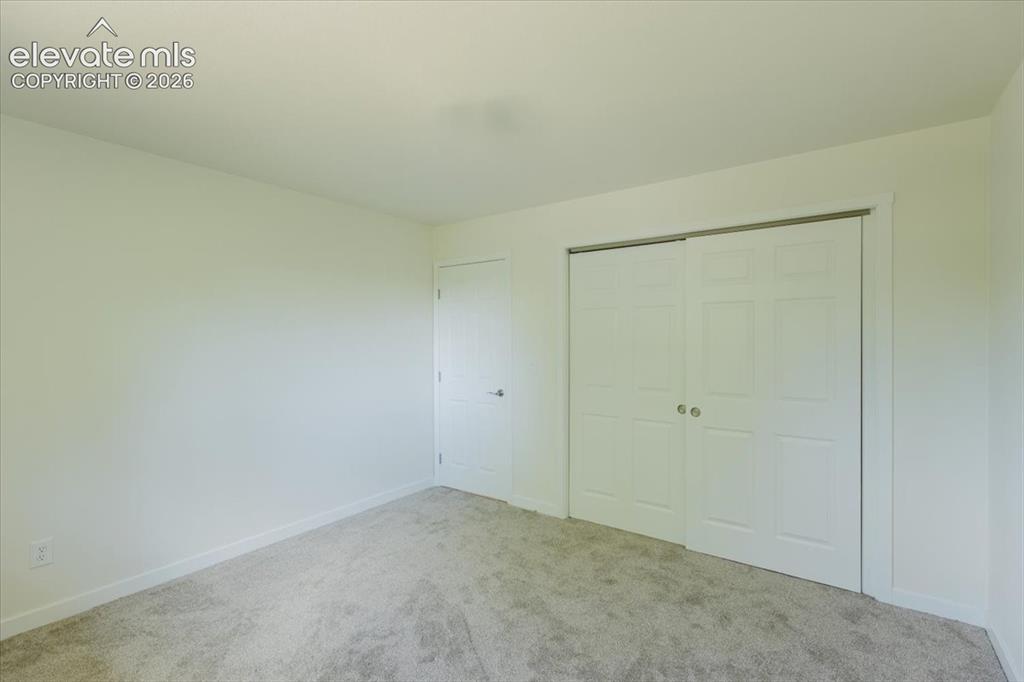 Image 17 of 27: Neutral-toned wall-to-wall carpeting complements the white walls and trim