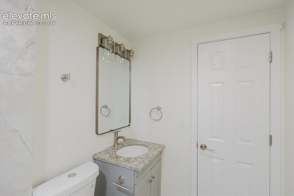 Image 19 of 27: Bathroom featuring a gray vanity with a granite-style countertop and underm