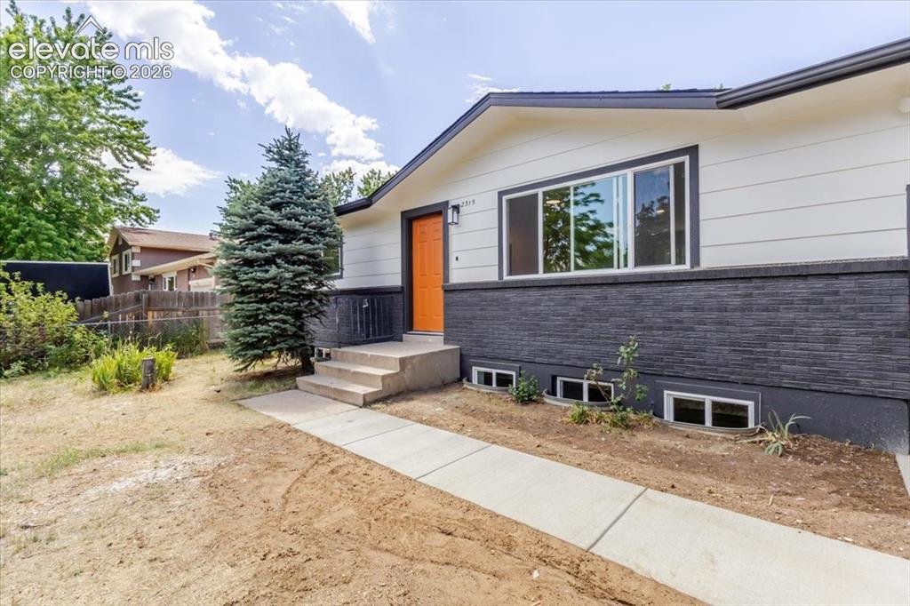 Image 2 of 27: Modern exterior featuring light-colored siding and a dark stacked stone fac