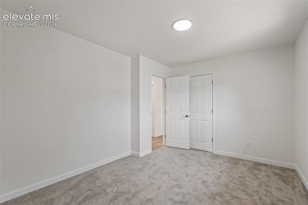 Image 22 of 35: Interior room featuring plush gray carpeting, white painted walls, and brig
