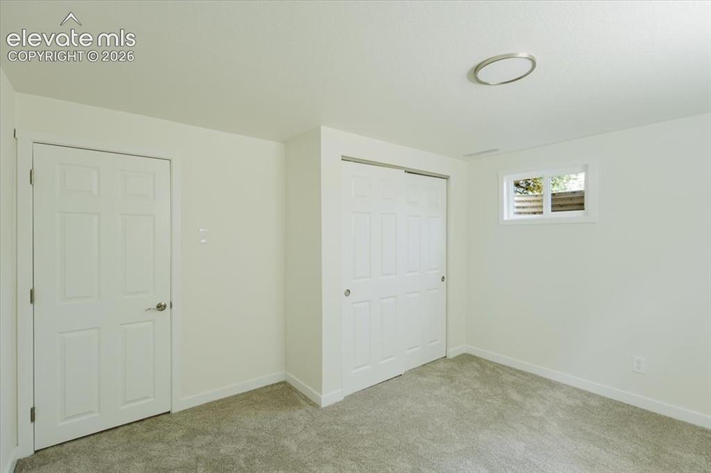 Image 26 of 27: Carpeted room with white walls, a six-panel door, sliding closet doors, a h