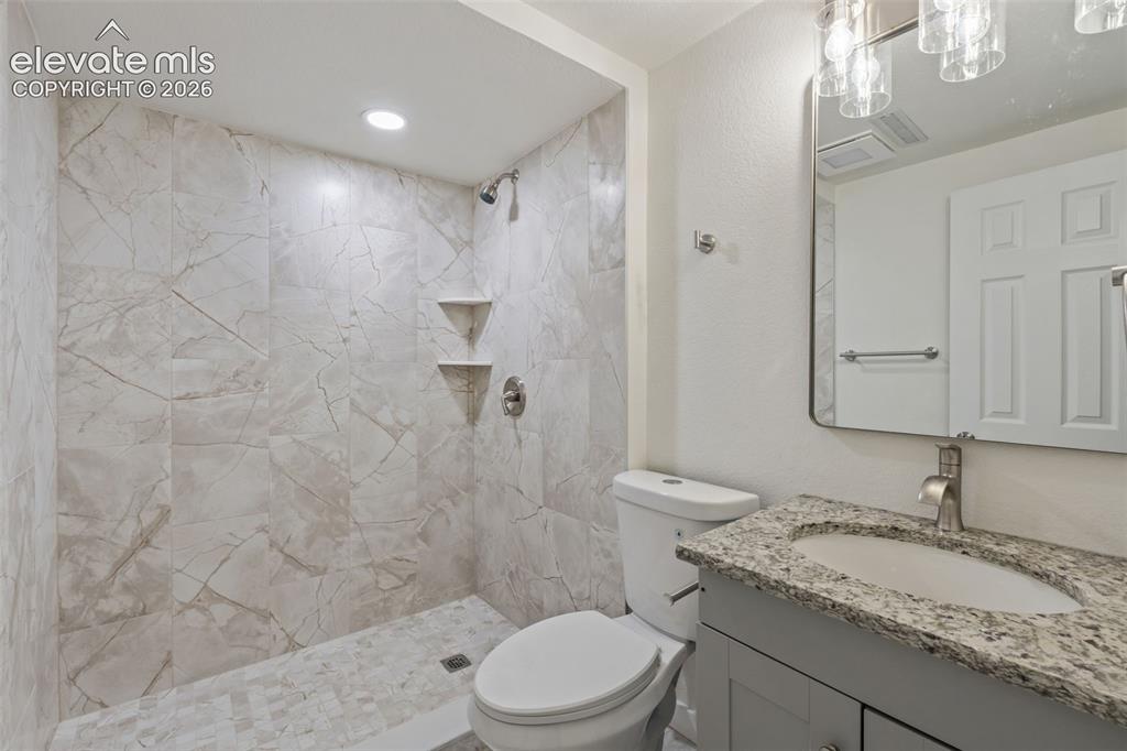 Image 28 of 35: Shower with large format porcelain tile walls and mosaic tile flooring, fea