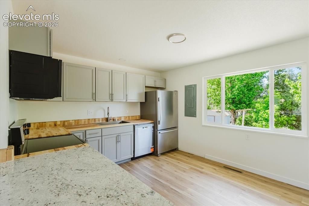 Image 3 of 27: Kitchen featuring light gray cabinetry, stainless steel appliances, wood-fi