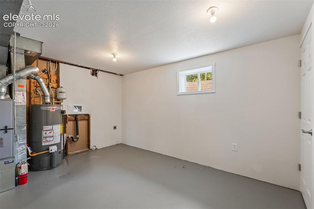 Image 31 of 35: Basement area featuring a white paneled door, a white-framed window, and pa