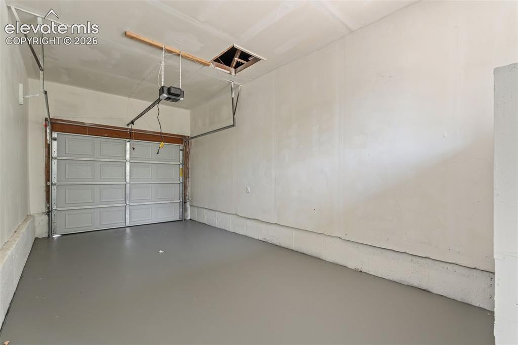Image 33 of 35: Garage space featuring a paneled overhead door, an automatic door opener, l