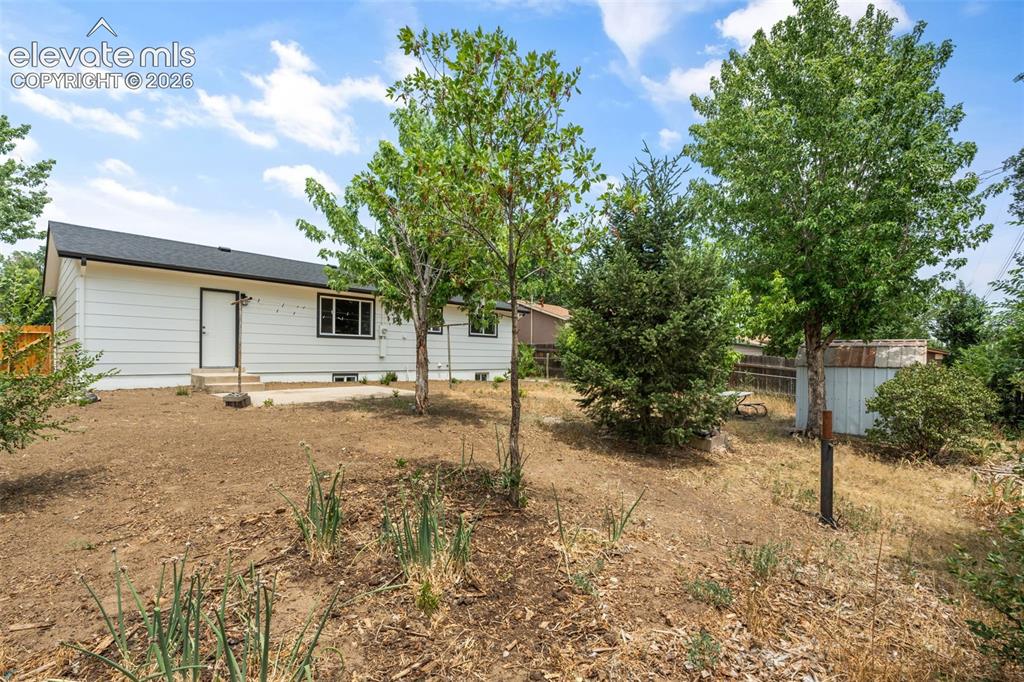 Image 35 of 35: Rear exterior featuring white siding, a dark roof, and a concrete patio