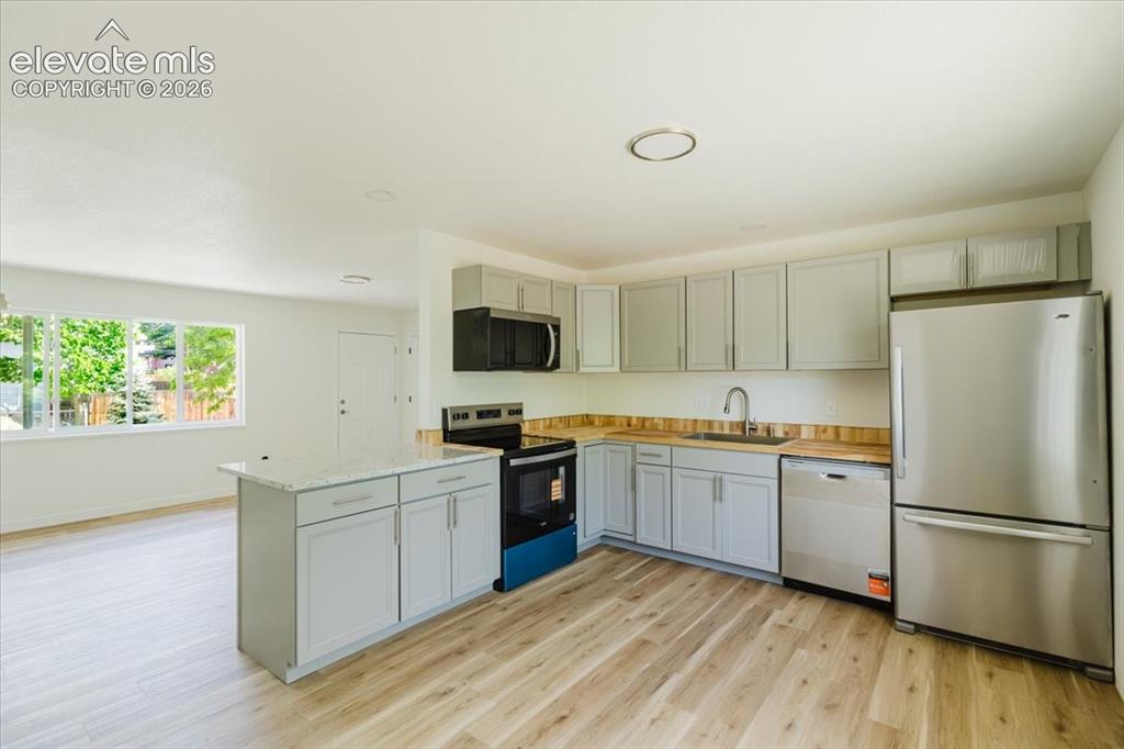 Image 4 of 27: Modern kitchen featuring stainless steel appliances, light gray cabinetry, 