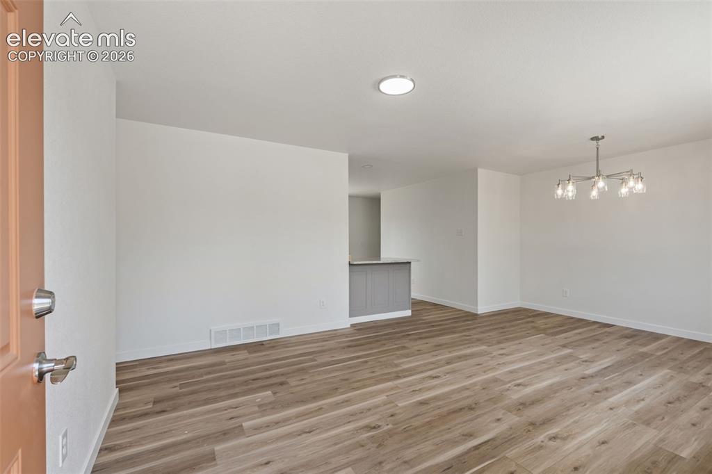 Image 4 of 35: Spacious room featuring wood-finish flooring, white walls, and a recessed c