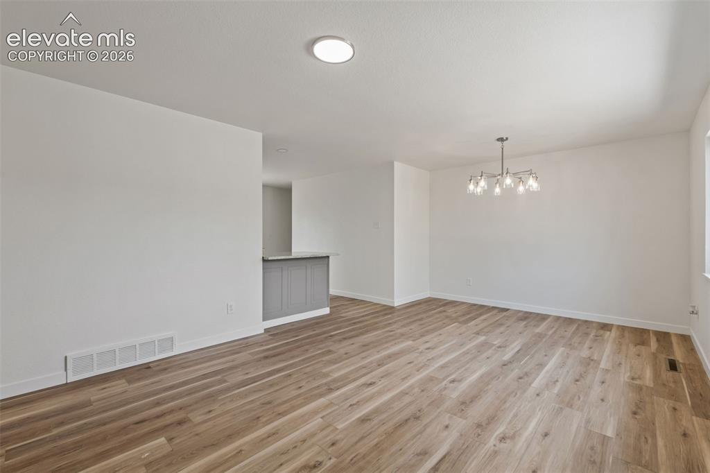 Image 5 of 35: Spacious room featuring wood-finish flooring, white baseboards, and a conte
