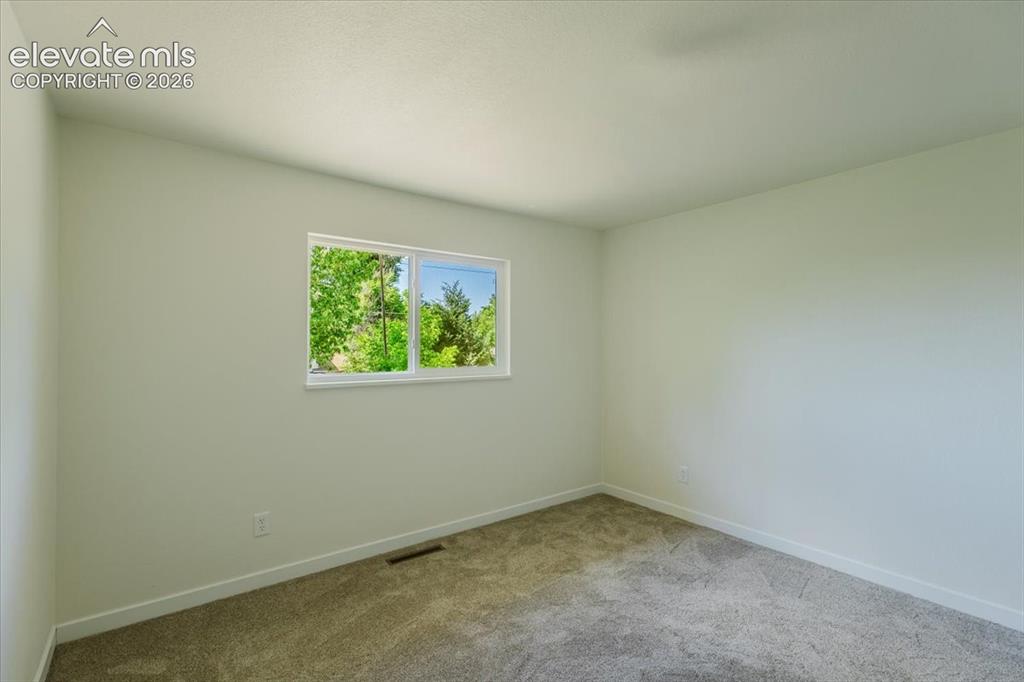 Image 7 of 27: Room featuring light neutral wall paint, white trim, and gray carpet floori