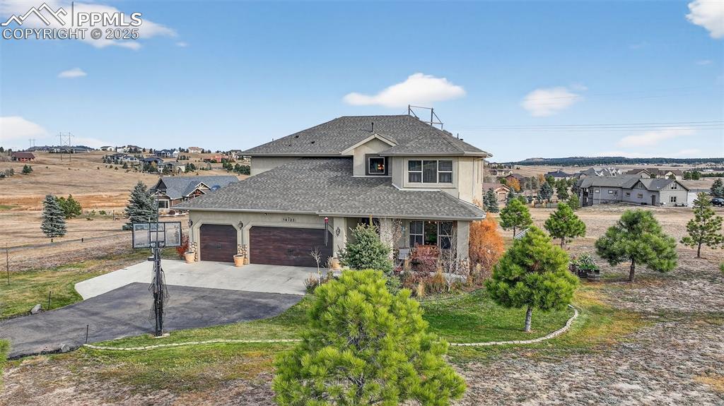 Caption: View of front of house featuring driveway, a shingled roof, stucco siding, an attached garage, and a