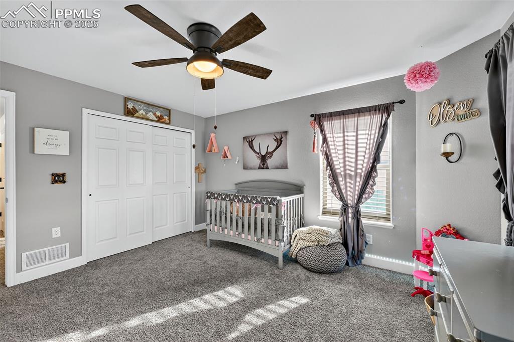 Image 20 of 39: Bedroom featuring a crib, carpet flooring, a closet, and a ceiling fan