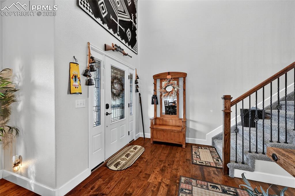 Image 4 of 39: Foyer featuring dark wood-type flooring, stairs, and a high ceiling