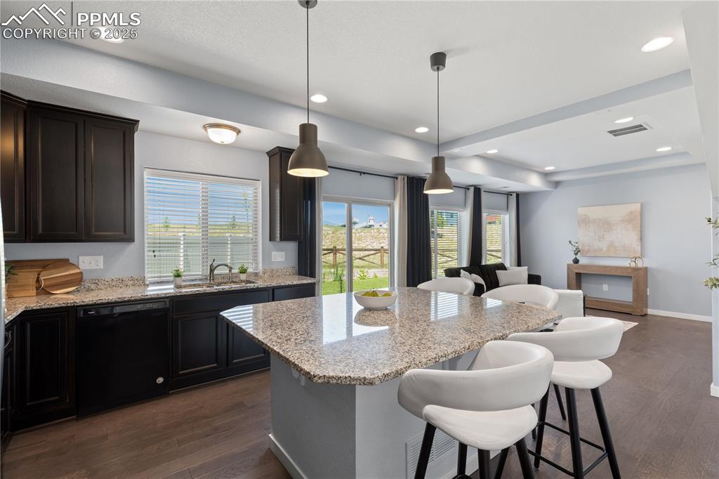 Image 10 of 33: Kitchen featuring black dishwasher, dark wood-style flooring, a kitchen bar