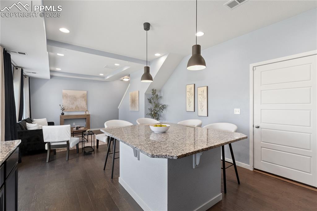 Image 11 of 33: Kitchen featuring a kitchen breakfast bar, dark wood-style flooring, light