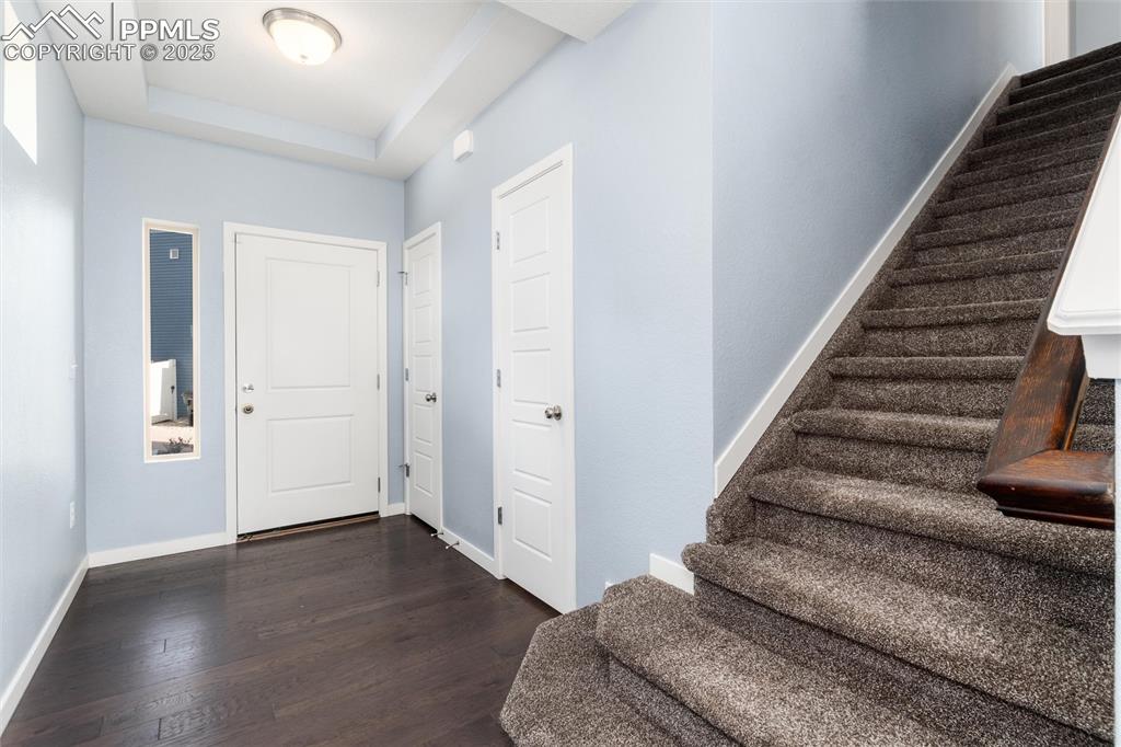 Image 13 of 33: Foyer entrance with stairs, dark wood-type flooring, baseboards, and a tray