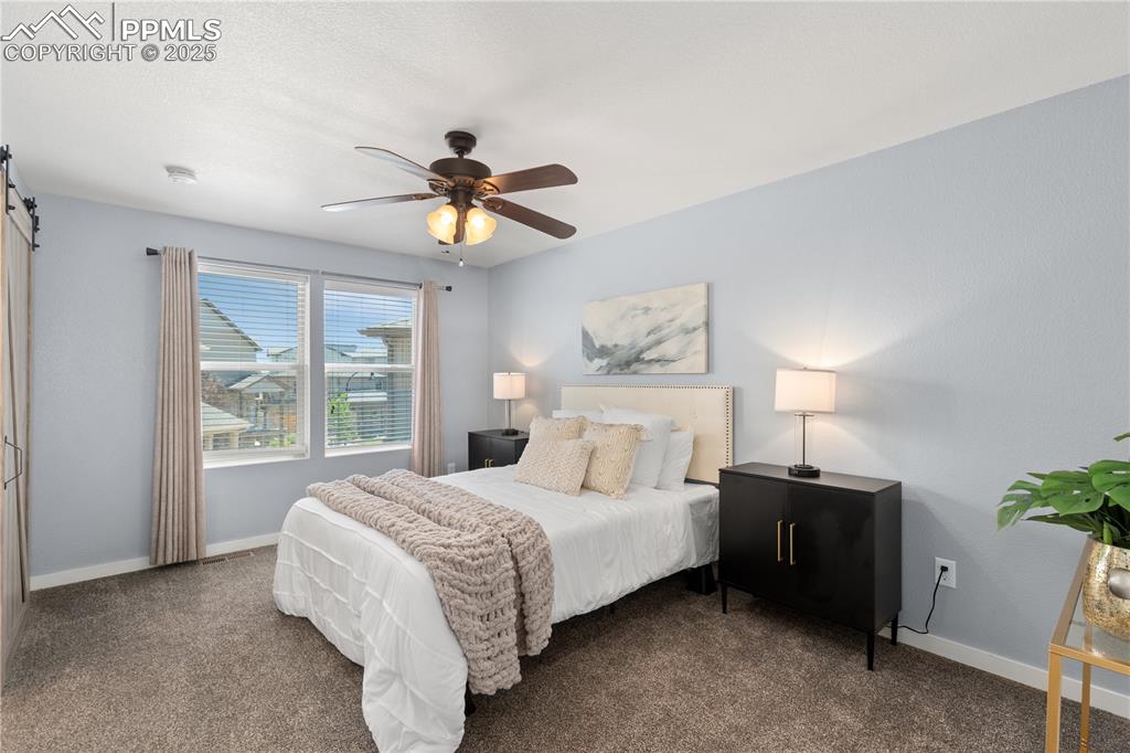 Image 15 of 33: Bedroom with carpet floors, a barn door, and ceiling fan