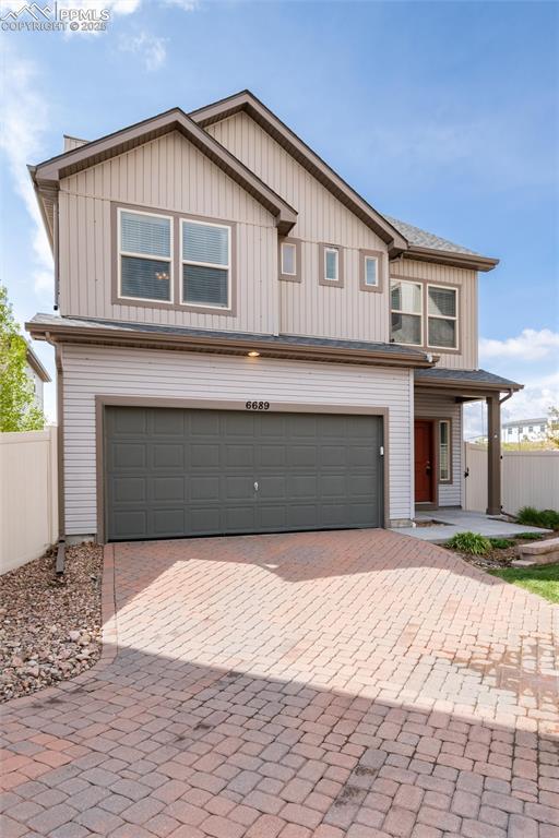 Image 3 of 33: View of front facade featuring a garage, decorative driveway, and board and