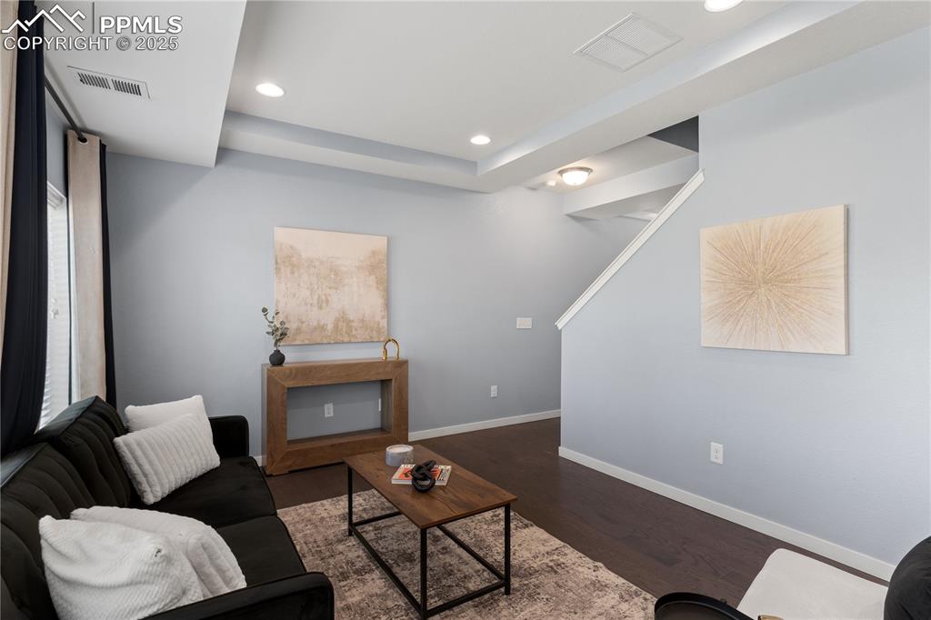 Image 7 of 33: Living room featuring dark wood-style flooring, recessed lighting, and a tr