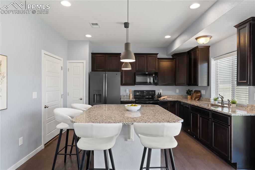 Image 8 of 33: Kitchen featuring black appliances, dark brown cabinets, dark wood finished