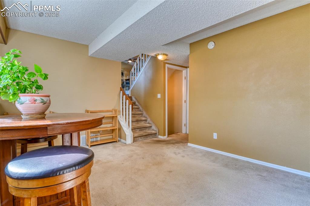 Image 20 of 38: Basement featuring stairway, carpet floors, and a textured ceiling