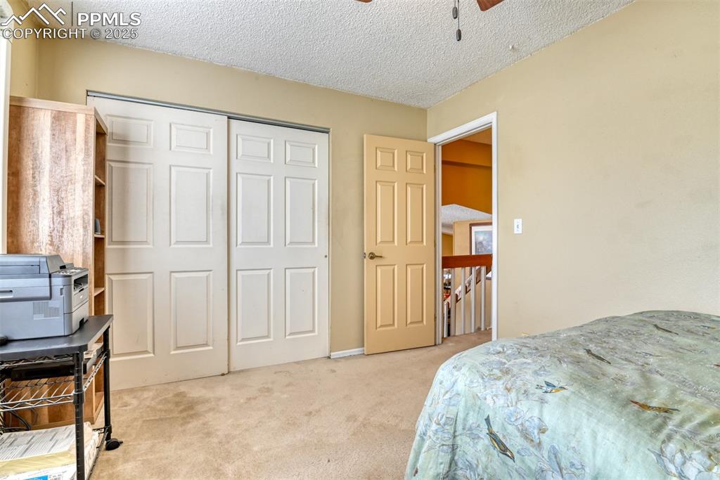 Image 21 of 38: Bedroom featuring light carpet, a textured ceiling, a ceiling fan, and a cl