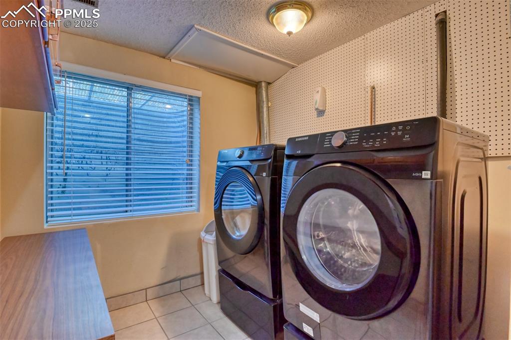 Image 32 of 38: Laundry room with tile patterned floors, a textured ceiling, and independen