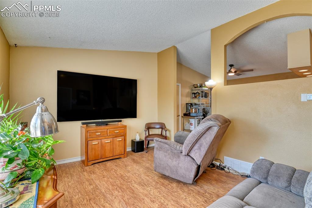 Image 4 of 38: Main level Living area featuring light wood finished floors, lofted ceiling