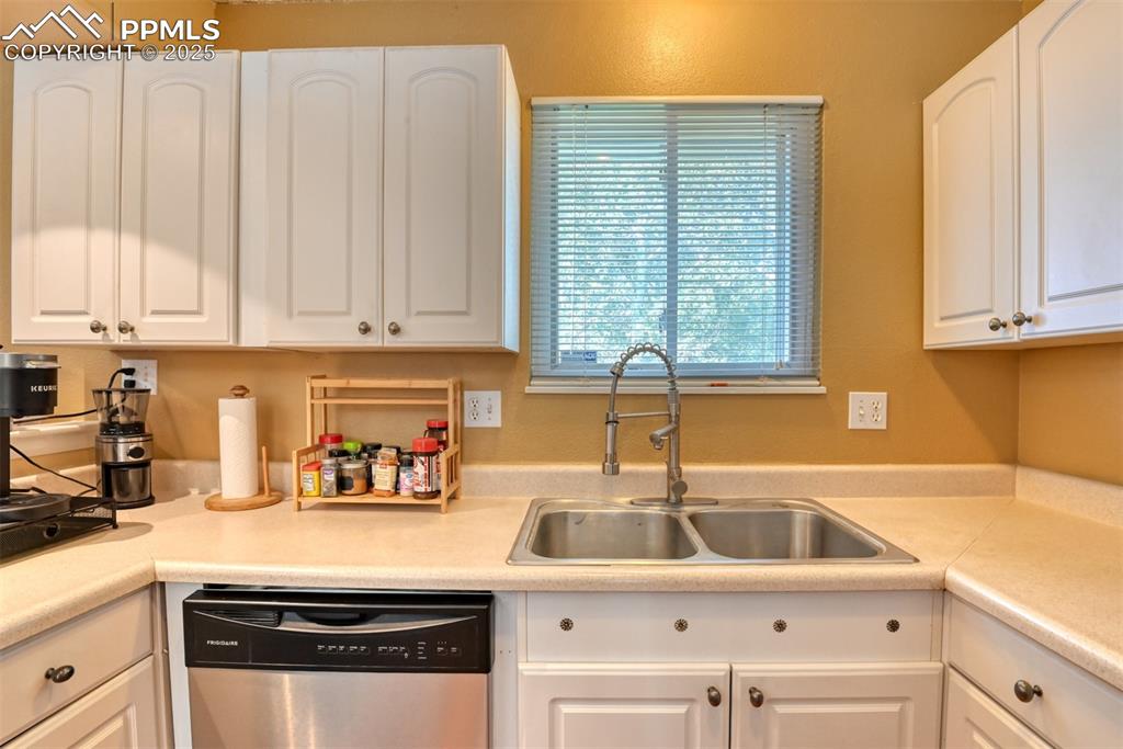Image 7 of 38: Kitchen featuring dishwasher, light countertops, and white cabinets