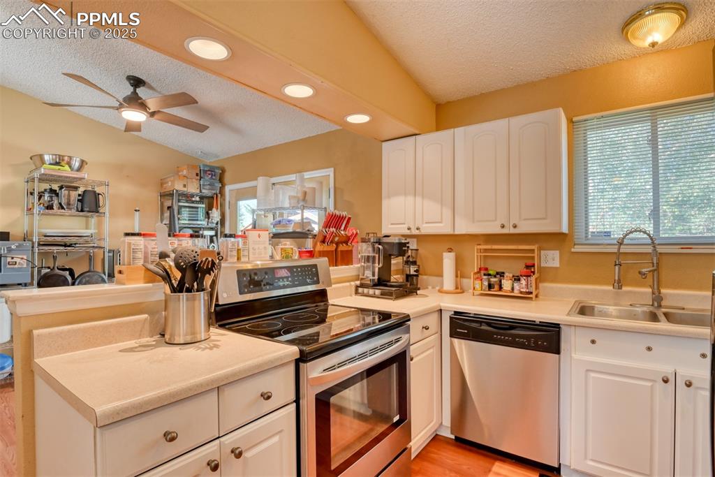 Image 8 of 38: Kitchen with stainless steel appliances, a textured ceiling, white cabinetr