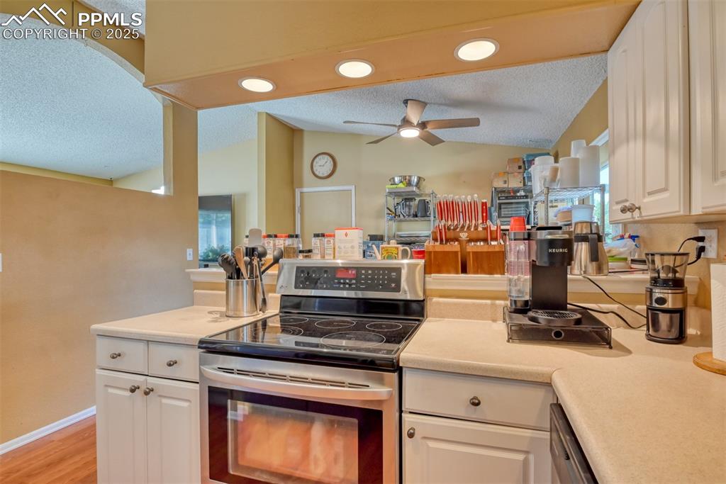 Image 9 of 38: Kitchen with electric range, a textured ceiling, light countertops, white c