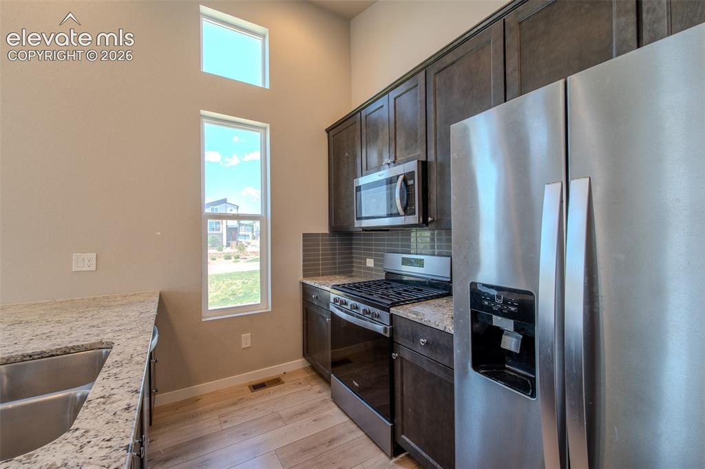 Image 20 of 46: Double stainless steel sink, gas range oven, built-in microwave, and side b