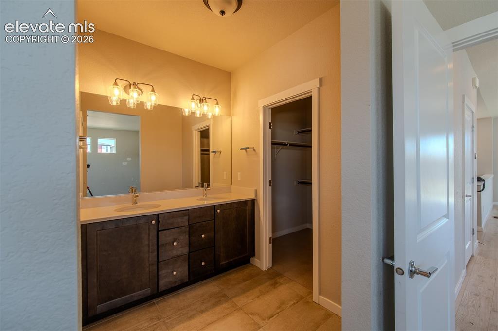 Image 26 of 46: The Primary Bathroom has a dual sink vanity, mirror, and tiled shower.