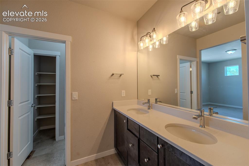 Image 27 of 46: Primary Bathroom vanity with dual sinks, mirror, and modern light fixtures.