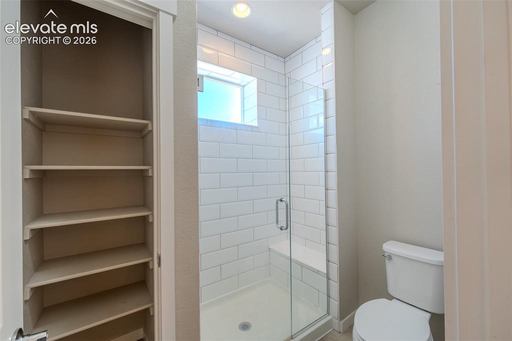 Image 28 of 46: Primary Bathroom with linen closet and enclosed, tiled shower with built-in