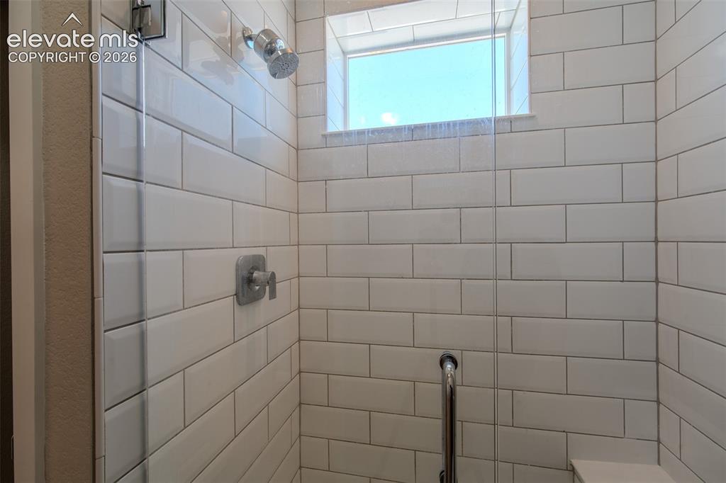 Image 29 of 46: White subway tiled shower with built-in sink.