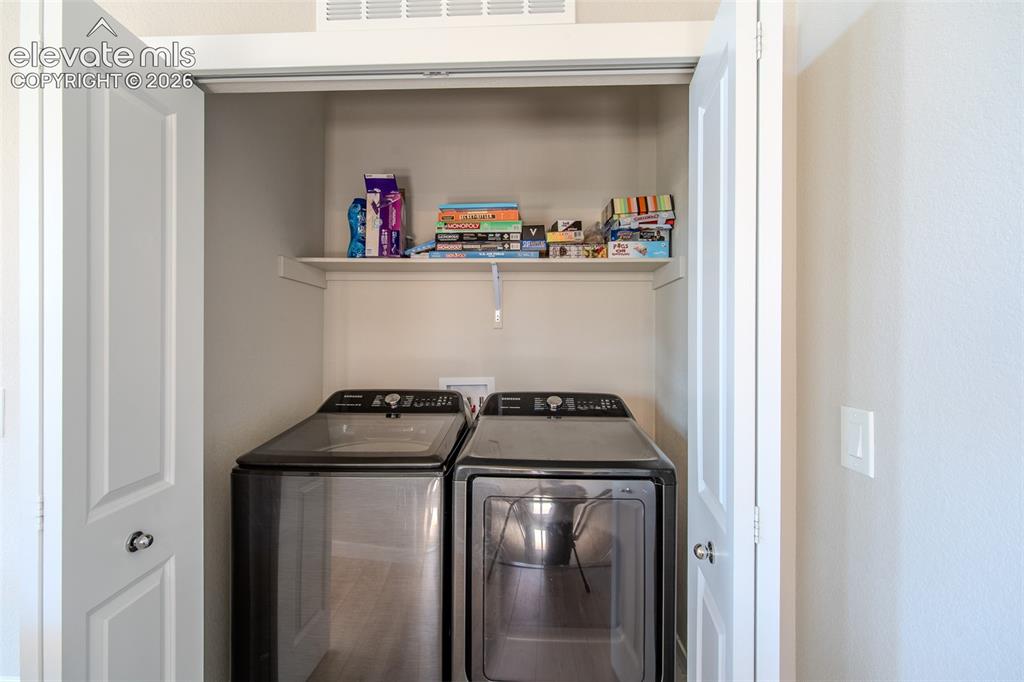 Image 32 of 46: Upper Level Laundry Closet with built-in shelf and washer and dryer include