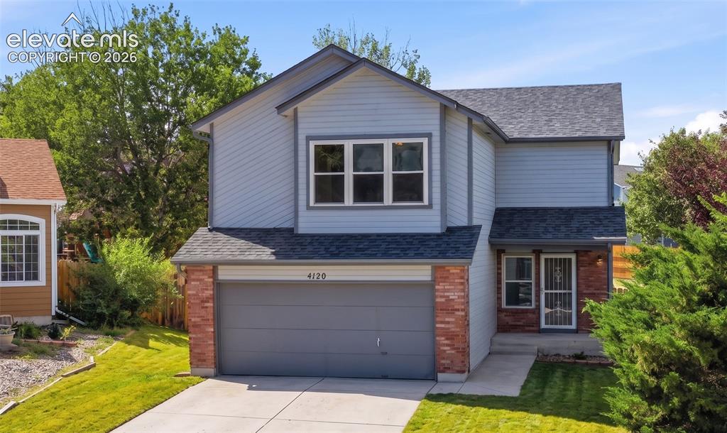 Caption: Two-story residence featuring light blue siding, brick accents, and a dark shingle roof
