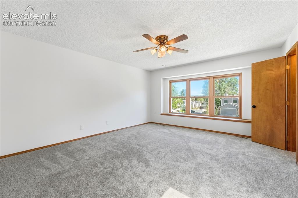 Image 16 of 47: Spacious room featuring light gray carpeting, a wide window with faux wood