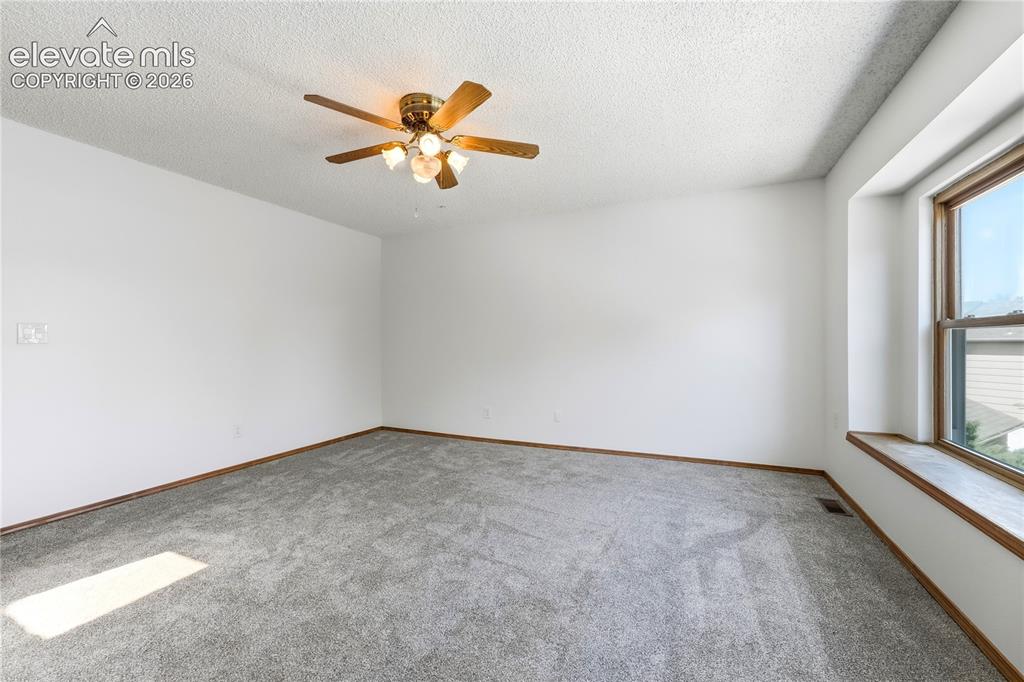 Image 19 of 47: Spacious room featuring light gray carpeting, a wide window with faux wood