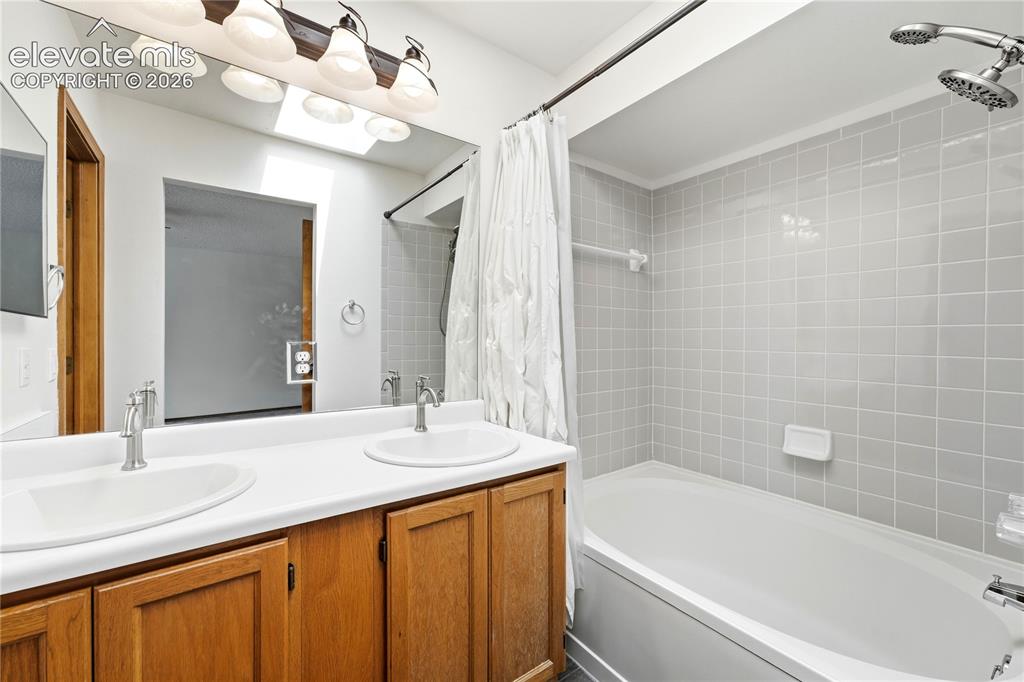 Image 20 of 47: Double vanity with integrated sinks, a full-width mirror, and a skylight