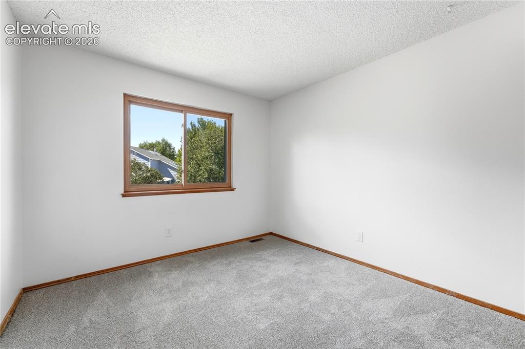 Image 25 of 47: Wall-to-wall carpeting in a neutral tone, white painted walls, and faux woo