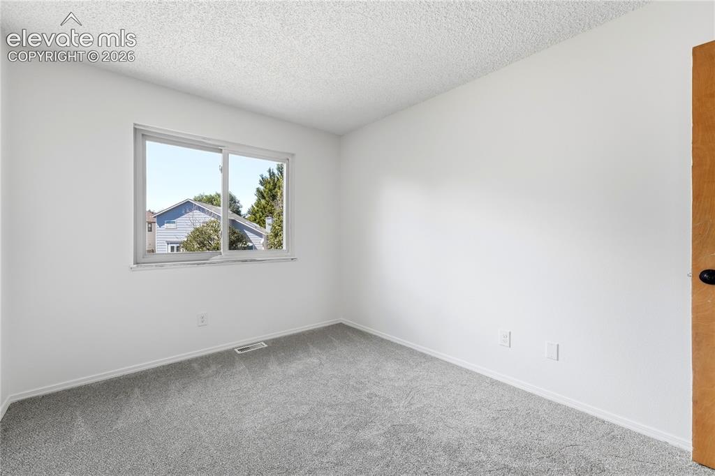 Image 29 of 47: Wall-to-wall carpeting in a neutral tone, white painted walls, and a single