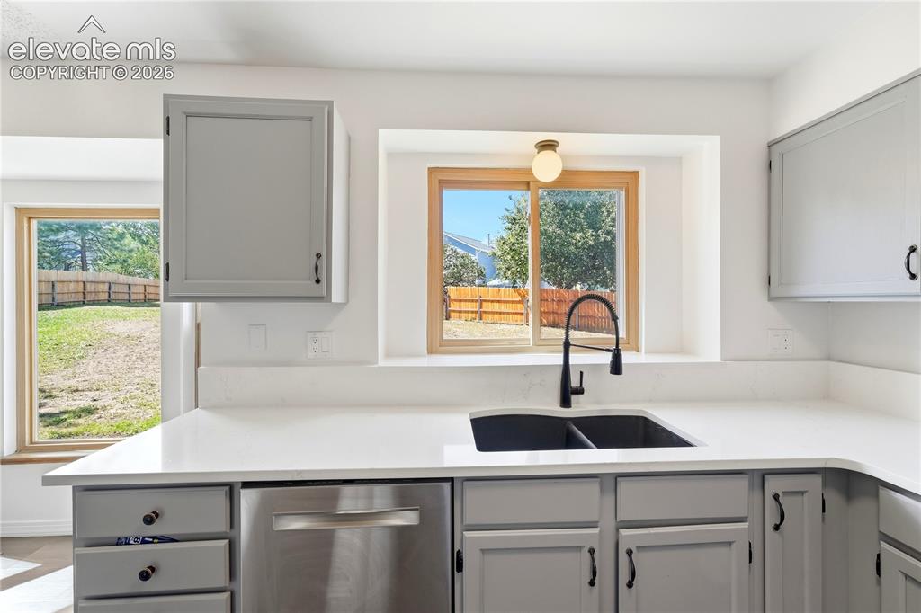 Image 4 of 47: Kitchen featuring gray cabinetry, stone quartz countertops, stainless steel