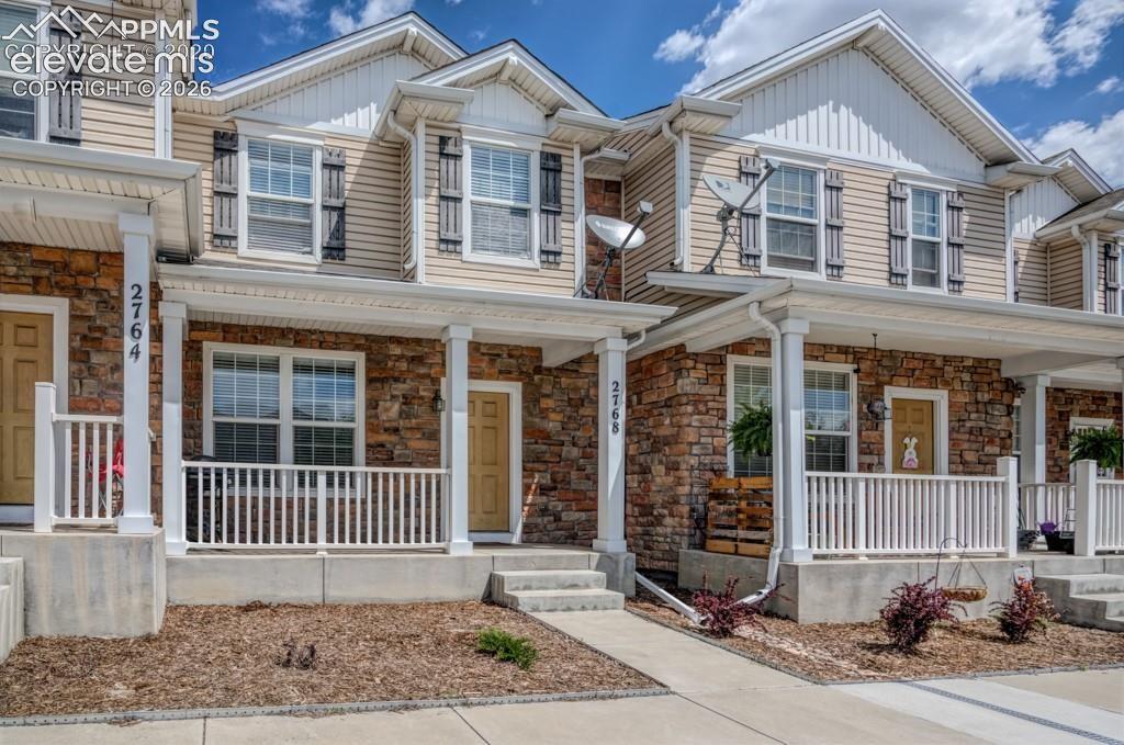 Caption: Exterior featuring a stone and siding facade, white columned porch, white railings, decorative windo
