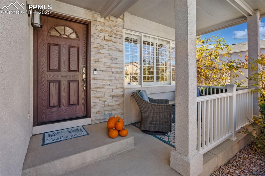 Image 11 of 43: Doorway to property with stone siding and a porch