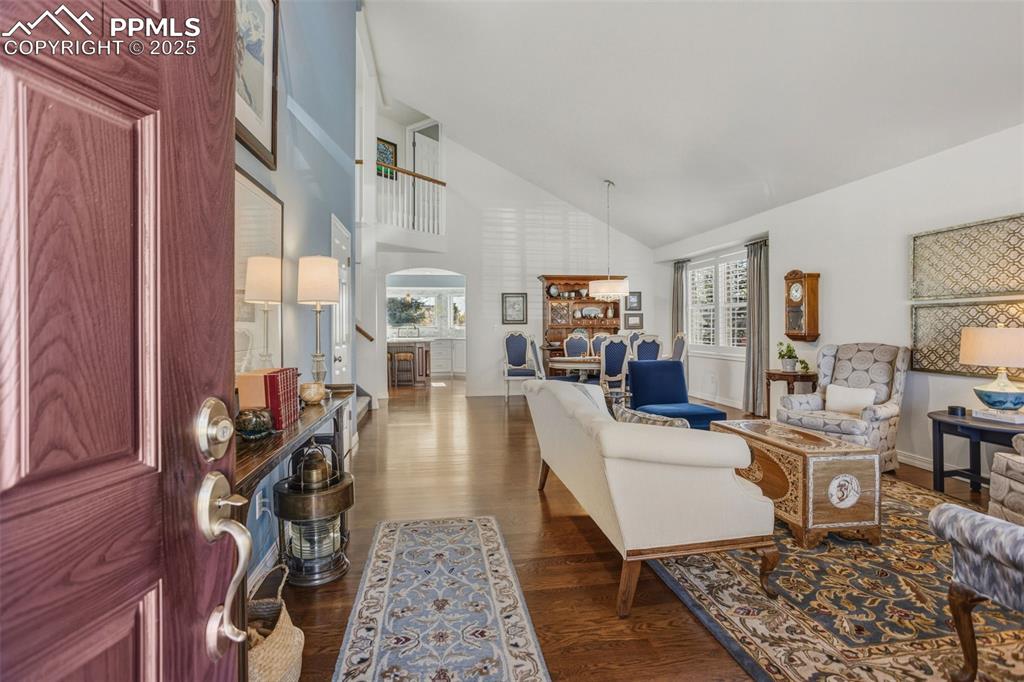 Image 12 of 43: Living area featuring dark wood-style flooring, high vaulted ceiling, and a